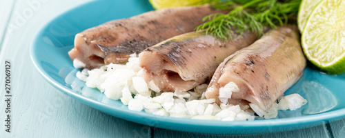 Photography Freshly salted herring fish, traditional dutch delicacy called hollandse nieuwe on turquoise plate and wooden background
