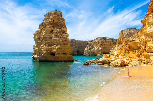 Young woman with blond hair and red bikini standing on beautiful beach Praia de marinha in Algarve, Portugal