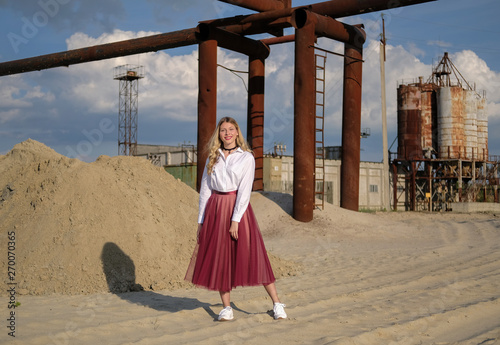 beautiful young girl on the background of industrial landscape and old construction equipment. portrait in grunge style. the concept of loneliness and the world of technology.