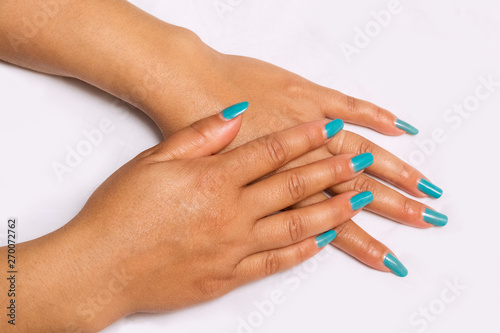 Beautiful closeup of hands of a young woman with long Blue manicure on nails.i