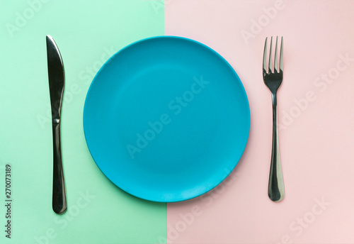 Empty blue plate fork and knife on duotone green pink background. Healthy diet meal planning concept. Mockup template. Creative foot poster with copy space