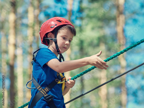 European boy on the rope way in the forest.