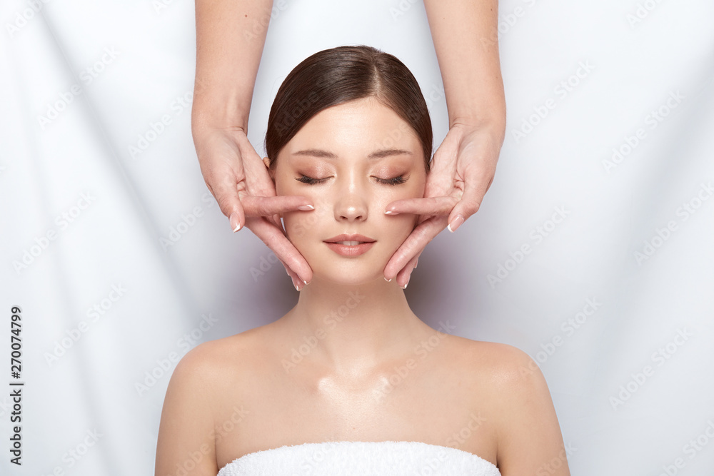 lovely woman having face theraphy with beautician on white