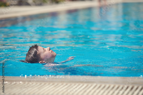 Swimming in pool. Boy is laying with his face up while swimming backstroke.