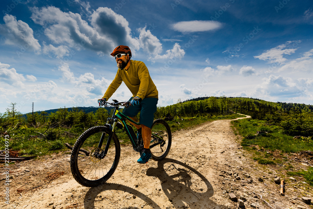 Mountain biker riding on bike in spring mountains forest landscape. Man cycling MTB enduro flow trail track. Outdoor sport activity.