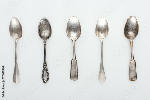 top view of shiny aged silver empty spoons in row on white background