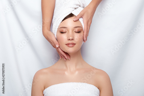 beauty master holding woman's face that lying down on white, head and face treatment for women, client of spa theraphy
