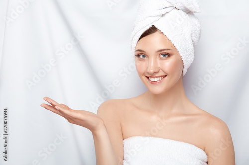 attractive young lady in bath towel on head pretending that she holding something on her arm, copy space, pretty girl keeps arm near shoulder
