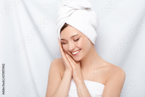 pretty girl in bath towel compose her arms near face and laughs with her eyes closed, happy woman after spa procedures