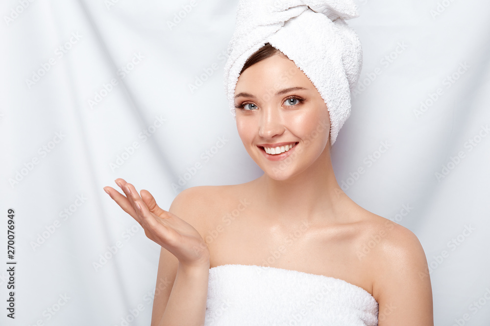 pretty girl with perfect smile in bath towel looking to the camera and holding her hand, copy space, spa and facecare treatment