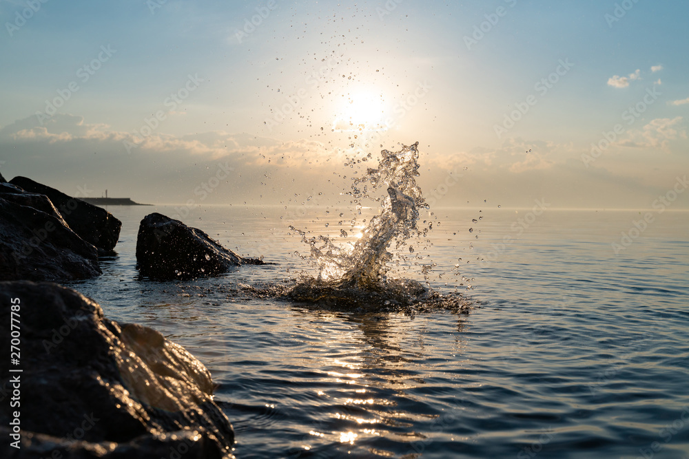 big beautiful splash of water in the sea at sunset. natural desktop background