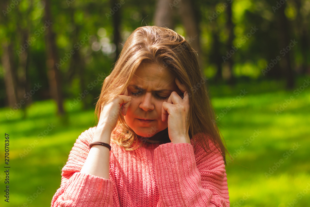 Young woman making a self-massage while having a temple headache – Teen having head pain in nature Young woman making a self-massage while having a temple headache – Teen having head pain in nature