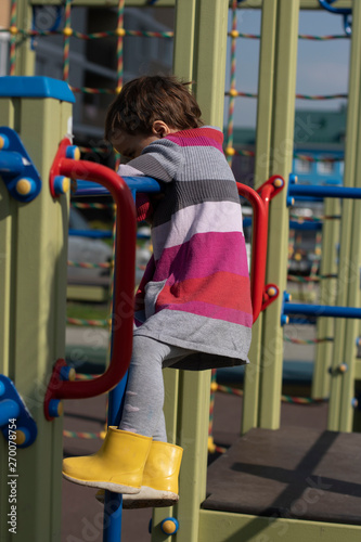 The child on the Playground. Childhood and game. A little girl climbs ladder and Playground