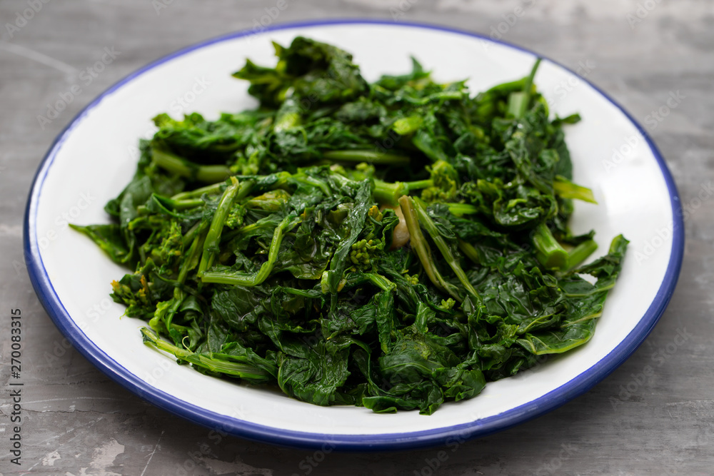 boiled greens with garlic on white plate on ceramic background boiled greens with garlic on white plate on ceramic background