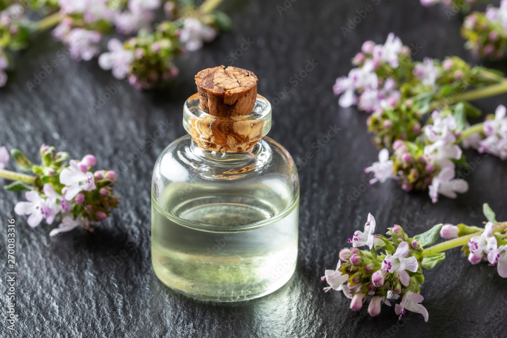 A bottle of thyme essential oil with fresh thyme A bottle of thyme essential oil with fresh thyme