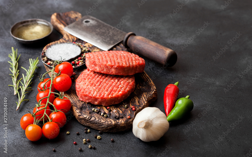 Fresh raw minced homemade farmers grill beef burgers on vintage chopping  board with spices and herbs and meat hatchet on black board. Oil, garlic  and tomatoes. Stock Photo | Adobe Stock