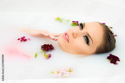 beautiful model woman face make up close up in milk bath beauty care and spa concept with flowers