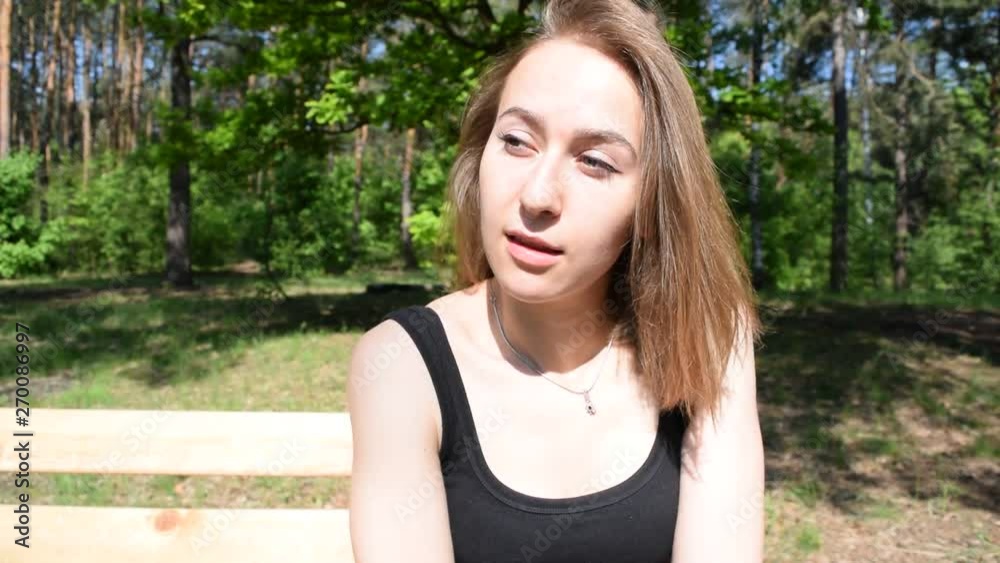 Young girl sitting on a wooden bench in the woods. Young girl sitting on a wooden bench in the woods.