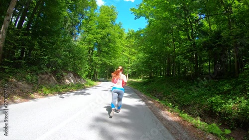 Wallpaper Mural Wide forward tracking shot of an overweight woman running on the sunny road surrounded by trees in the summer Torontodigital.ca