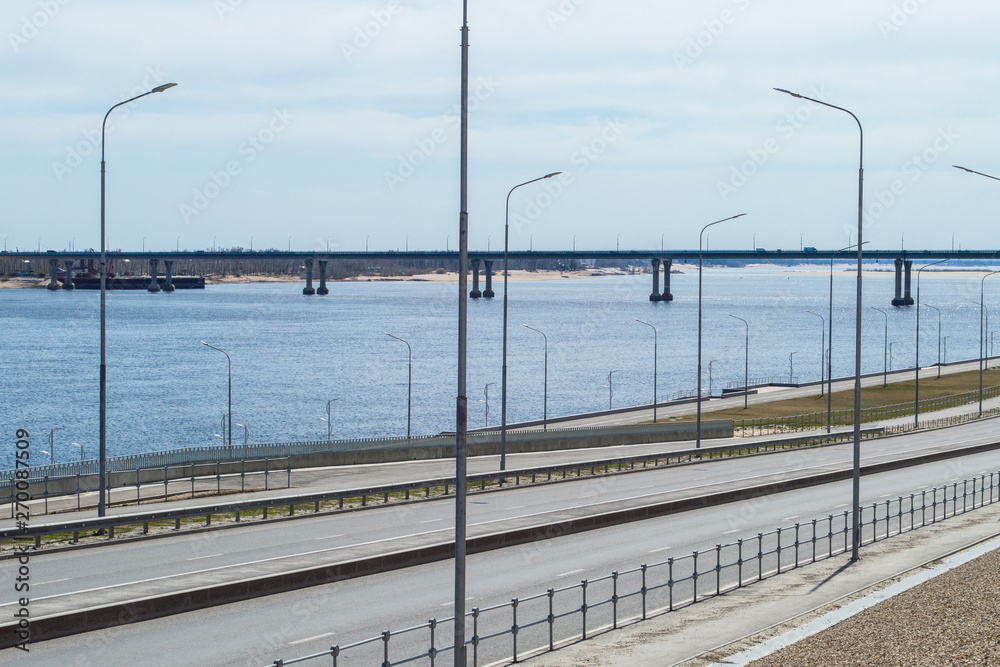 Obraz premium Panorama of big river, riverside with roadway and bridge across the river