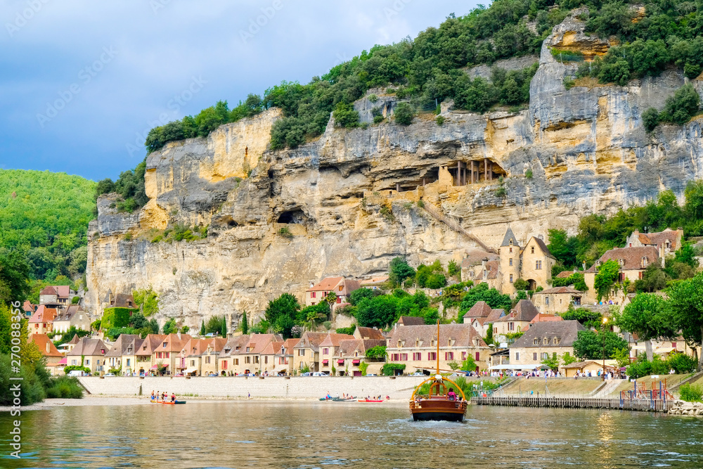 Village La Roque Gageac, France and embankment of the Dordogne River with gabare local boat.