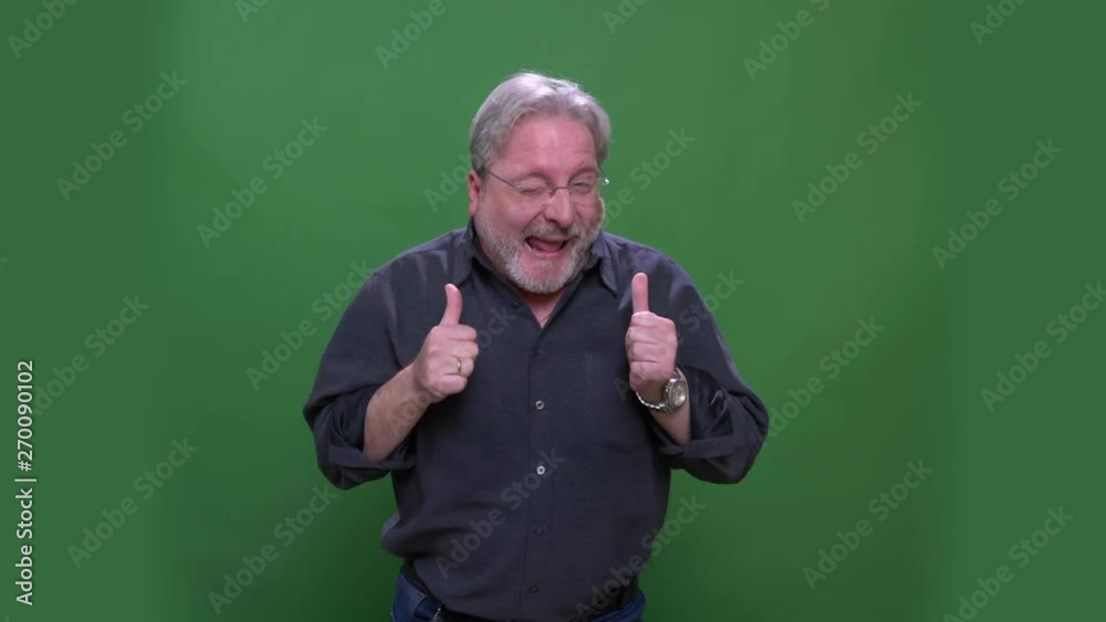 Senior gray haired american manin glasses dances and shows thumbs-up isolated on green chromakey background. Senior gray haired american manin glasses dances and shows thumbs-up isolated on green chromakey background.
