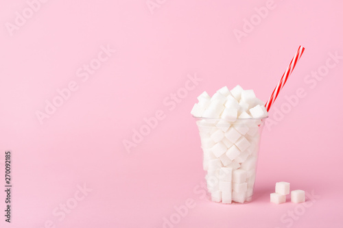 Shake Glass full of sugar cubes on pink background Unhealthy food concept