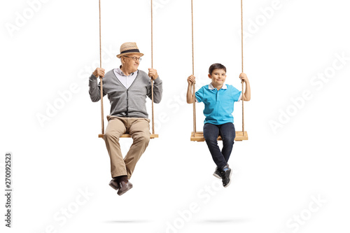 Grandfather looking at his grandson and sitting on wooden swings