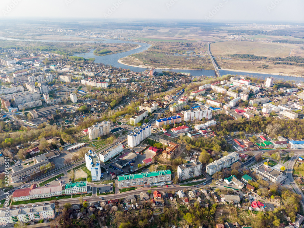 Panorama of a small town, river, forest, fields, road, bridge and sky. The photo was taken by a quadcopter, drone. Summer and spring. Skyview. Top view. Travel and tourism. Created by DGJ drone.