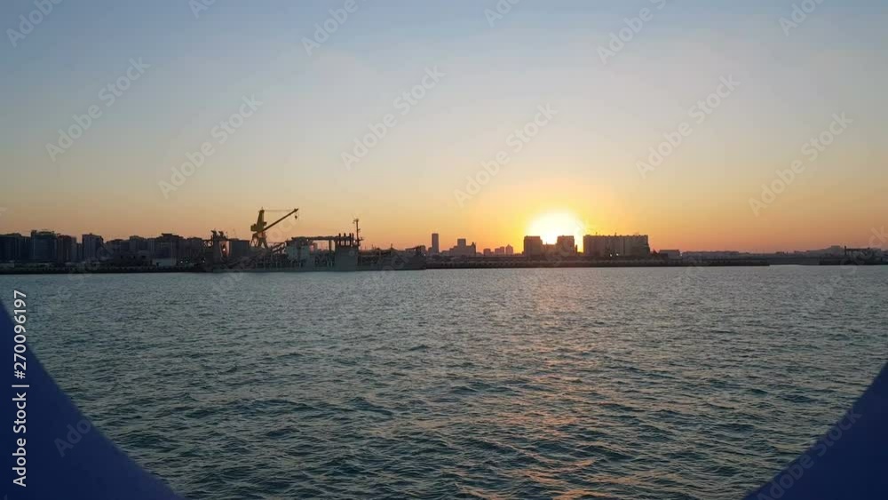 Sunset over the ocean and seaport. View of the ocean and the city from the cabin of a cruise liner. View of the sunset and the ocean through the porthole of the ship. Sunset over the ocean and seaport. View of the ocean and the city from the cabin of a cruise liner. View of the sunset and the ocean through the porthole of the ship.