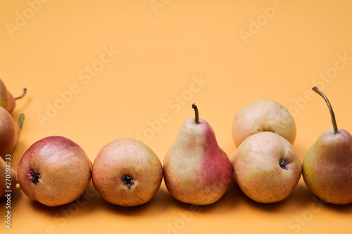 Pears placed as pattern on orange background. Colorful fruit pattern or background photo