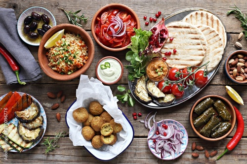 Obraz na plátně Middle eastern, arabic or mediterranean appetizers table concept with falafel, pita flatbread, bulgur and tomato salads, grilled vegetables, stuffed grape leaves,olives and nuts