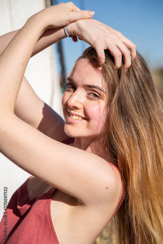 Fototapeta premium Portrait of young attractive woman in casual summer dress leaning on railing of balcony