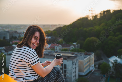 woman drinking coffee with beautiful view of sunset over lviv city in ukraine