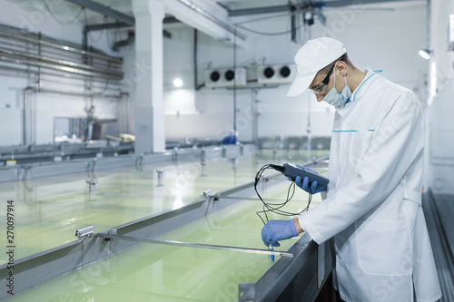 Fotografie man in a white robe and a cap make an inspection of dairy products