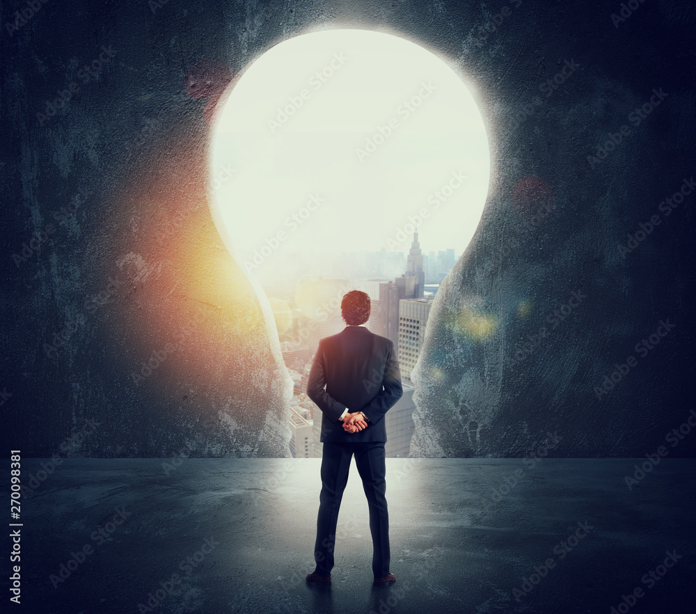 Fototapeta premium Businessman looks at a big hole on the wall shaped as a light bulb