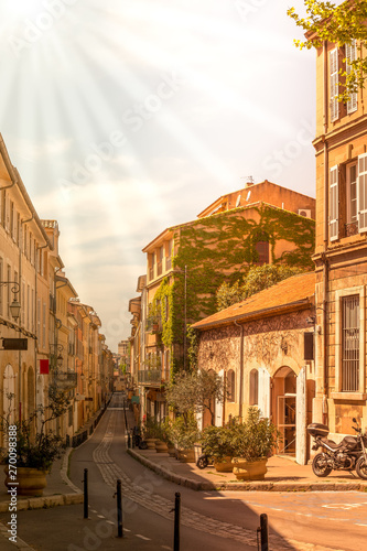 Quiet street in France - no people in a small street with ivy covered wall plants and sun-rays on an early morning in spring - deserted street in small french town - no people on french street