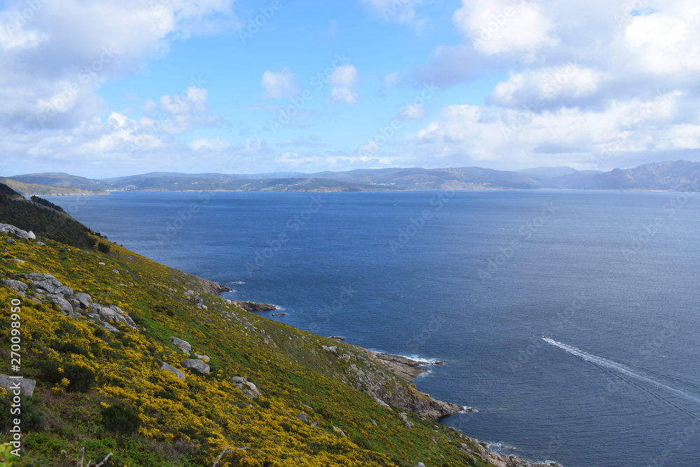 Acantilados y olas rompiendo contra las rocas en un día soleado parcialmente nublado en la costa atlántica de Galícia, España. 