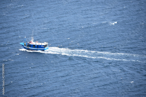 Escena de barco pesquero regresando al puerto después de un día de pesca. 