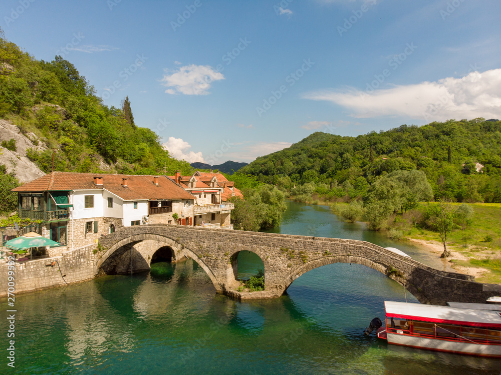 Aeral view to old bridge in the village Rijeka Crnojevica reflecting in the water in Montenegro. Stari most.