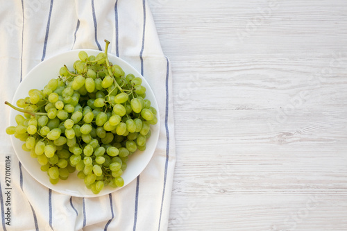 Φωτογραφία Green grape on a white plate on a white wooden surface, top view
