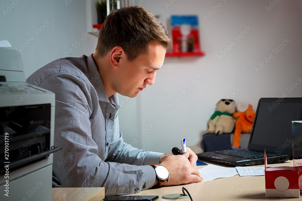 Obraz premium concentrated businessman taking notes in front of the laptop and other equipment in his modern office