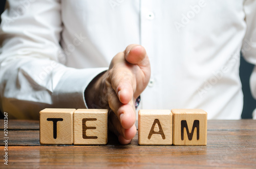 A man shares with his hand cubes with the inscription team. Dividing the collective into two parts or disbanding the team. Lack of leadership qualities and poor quality of business management.