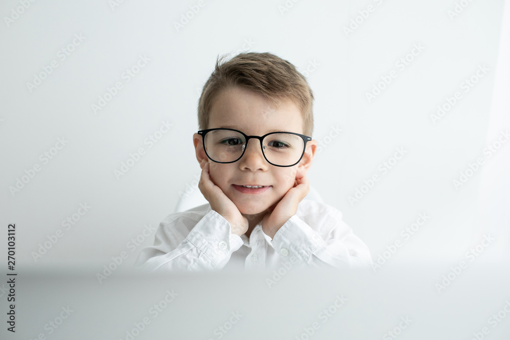 Cute little boy using laptop while doing homework against white background Cute little boy using laptop while doing homework against white background