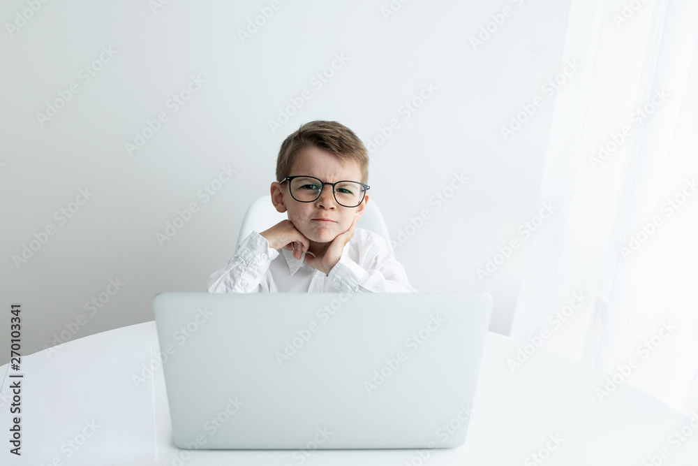 Cute little boy using laptop while doing homework against white background Cute little boy using laptop while doing homework against white background