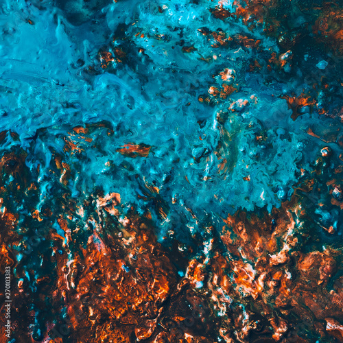 Abstract art texture background. Closeup of hazelnut brittle with colorful glaze. Glossy blue and brown paint with flowing effect.