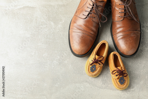 Brown leather shoes and children's shoes on grey background, space for text and top view