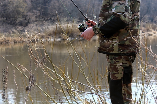 Fisherman in camouflage clothing, fishing on spinning.