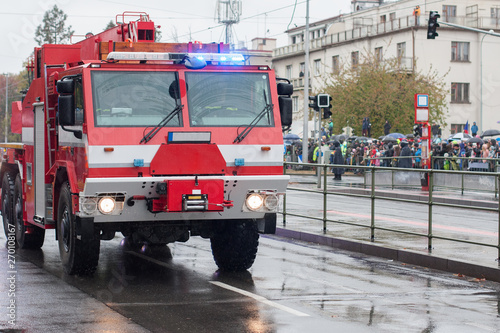 Fire brigade workers are riding fire truck crane on military parade