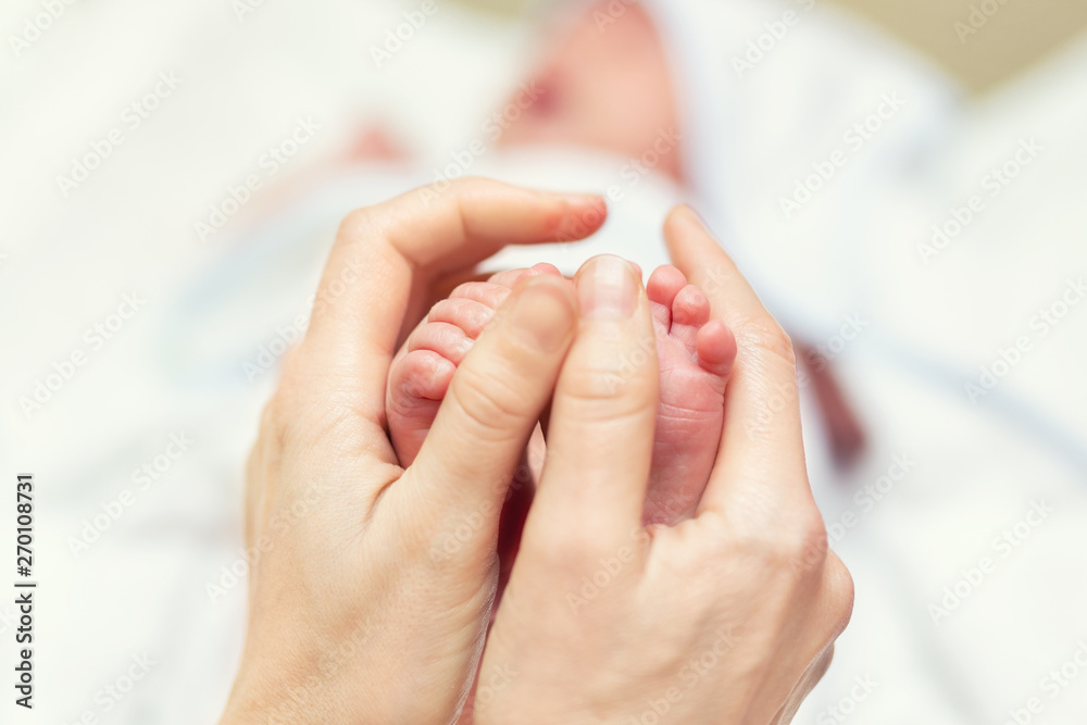 Mother making baby feet massage for newborn infant child. Mom massaging legs of small baby son.Children healthcare and happy parenthood Mother making baby feet massage for newborn infant child. Mom massaging legs of small baby son.Children healthcare and happy parenthood